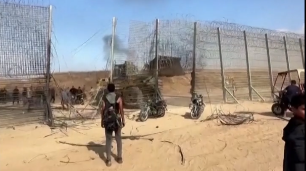 Video shows armed militants breaking through a hole in a wire fence section of the border and a bulldozer destroying part of the barrier