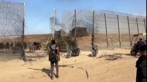 Un clip vidéo montre des hommes armés pénétrant dans une brèche dans une partie du grillage à la frontière, et un bulldozer montre également la destruction d'une partie de la barrière.